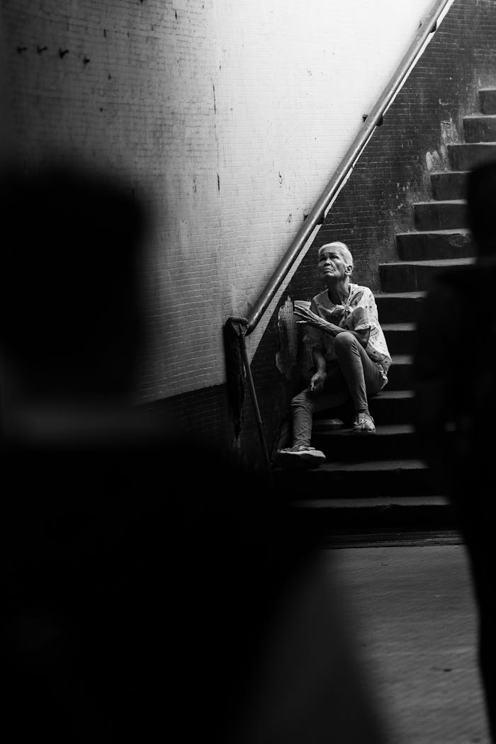 Black and white photograph of a man sitting on stairs in Manila subway, evoking solitude.